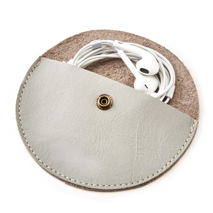 The Miina Medio Half-moon gray coin purse crafted with sustainably sourced materials, featuring a sleek and minimalist design with a curved silhouette. Perfect for carrying coins and small essentials while promoting eco-conscious living.
